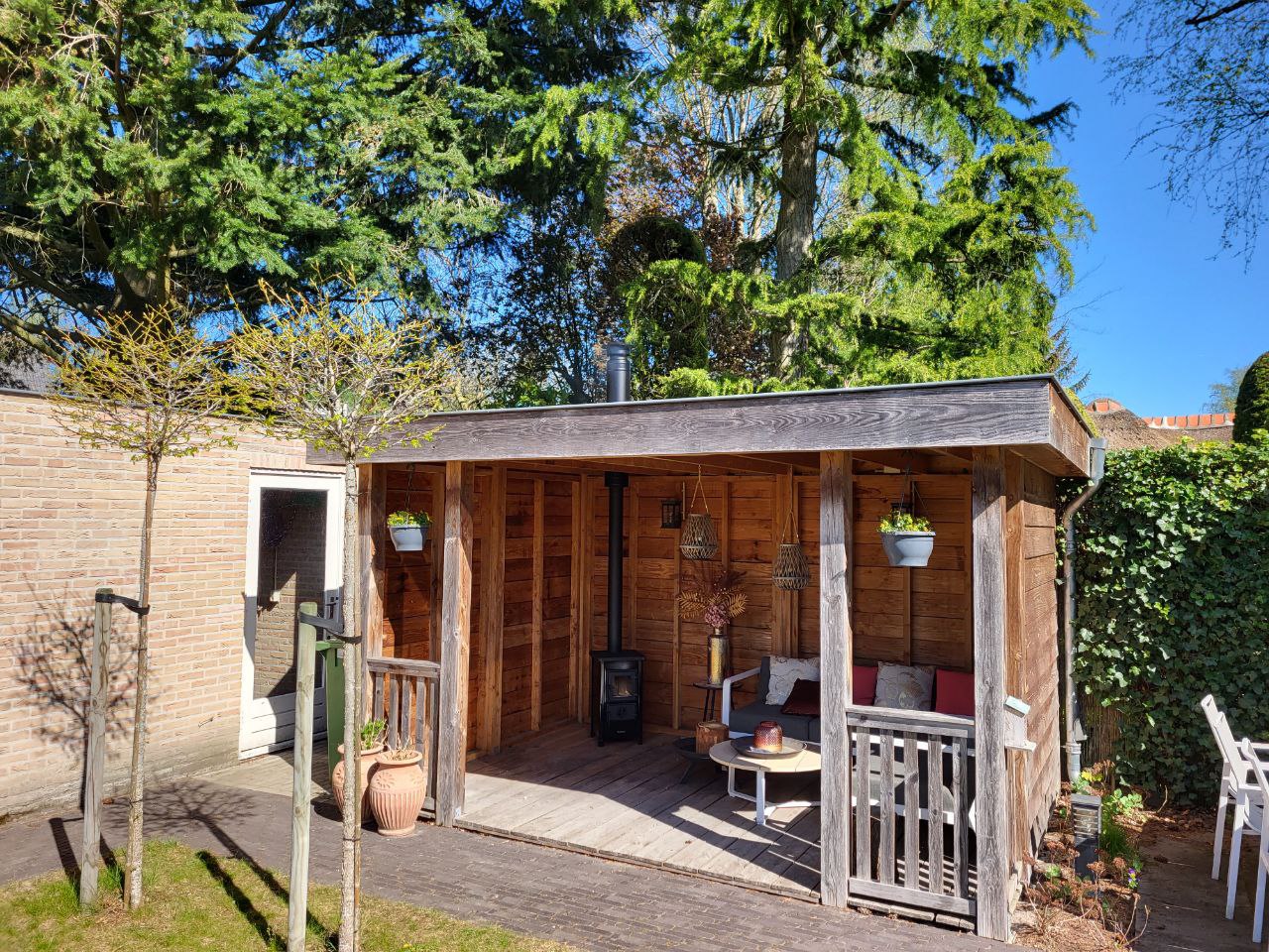 Overdekte veranda met houtkachel in de tuin.